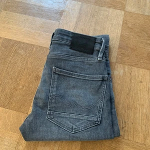 Grå jeans slim fit - Snygga grå jeans från Jack and Jones. Byxorna är knappt använda och är i väldigt fint skick. Det är storlek 28 30. 28 i midjan och 30 i längden. 