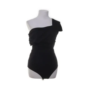 Svart asymmetrisk body  - Snygg svart body från H&M med cool asymmetrisk design och en axel. Materialet är mjukt och stretchigt med polyester och elastan som ger en skön passform. 