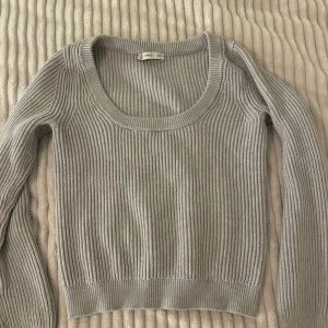 Grå ribbad stickad tröja från MNG - Säljer en grå stickad tröja från MNG i storlek S. Tröjan har ett ribbat mönster, rundad och bred halsringning samt långa ärmar. Perfekt för dig som gillar enkel och clean stil med lite edge. Passar dig som vill ha en basic men snygg tröja till garderoben.