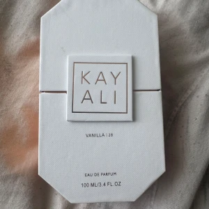 Kayali Vanilla | 28 Eau de Parfum 100ml - Kayali Vanilla | 28 Eau de Parfum i en lyxig, åttakantig glasflaska med guldiga detaljer. Doften har noter av vaniljorkidé, tonkaböna, brunt socker, amber woods och mysk. Flaskan rymmer 100 ml och kommer i en elegant vit kartong.