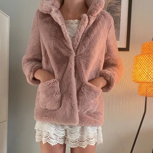 Rosa fluffig pälsjacka med huva - Supermysig rosa pälsjacka med huva och stora fickor framtill. Jackan har en loose passform och är tillverkad i mjukt syntetmaterial som ger en fluffig känsla. Perfekt för dig som vill ha en chill och trendig look under kyliga dagar.