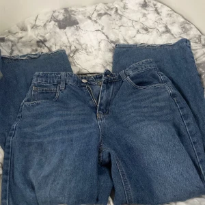 Blå jeans från Dazy, storlek M - Säljer ett par klassiska blå jeans från Dazy i storlek M. Modellen har raka ben, fem fickor och bälteshällor. Jeansen är tillverkade i jeansmaterial och har en snygg mörkblå tvätt. Perfekt för dig som gillar en enkel och tidlös look.
