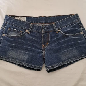 Basic mörkblåa jeansshorts g-rise - Basic jeansshorts som är väldigt low waist. Orangea detaljer. Köpt från en marknad i Thailand.