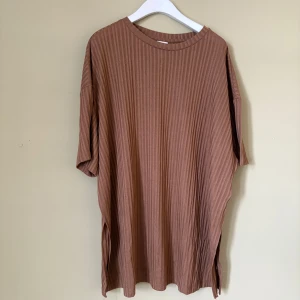 Ribbad brun t-shirt från H&M XL - Säljer en oversized ribbad t-shirt från H&M i storlek XL. Färgen är brun med vertikala ränder och modellen har korta ärmar och rund hals. Materialet är mjukt och känns skönt mot huden, perfekt för chill dagar. Passformen är loose och ger en avslappnad vibe.