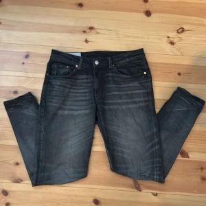 Svarta tapered jeans från H&M - Snygga svarta jeans från H&M med tapered och regular fit. De har klassisk femficksdesign, knapp och dragkedja i gylfen samt subtila slitningar för en cool look. Perfekta för dig som gillar stilrena och bekväma jeans med smalare ben.