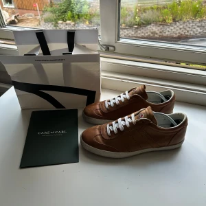 Bruna sneakers i skinn med vit sula - Snygga bruna sneakers i skinn med vita snören och vit platt sula. Klassisk och stilren design med diskreta sömmar och rund tå. Perfekta för dig som gillar en clean look med premiumkänsla.