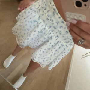Vit blommig kortkjol från Gina Tricot - Supersöt vit kortkjol från Gina Tricot med blått blommigt mönster. Kjolen har andvänts fåtal gånger 🤍 