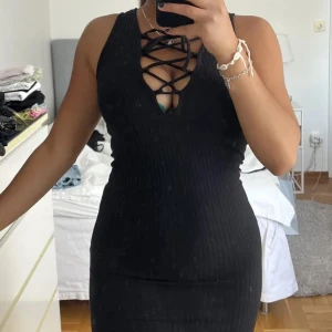 Svart strechig klänning  - Svart strethig klänning med knytning över bröstet 