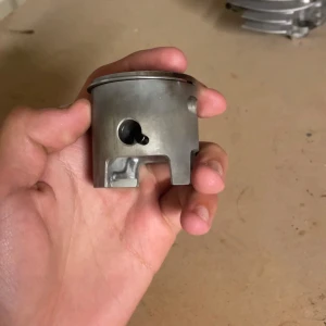 Athena big bore 70cc - Bilderna visar delar från en motor, bland annat en kolv, cylinder och cylinderhuvud. Dessa komponenter är perfekta för dig som gillar att meka med fordon och vill lära dig mer om motorteknik. Passar dig som är intresserad av teknik och motorer.