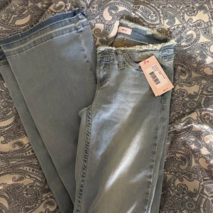 Bootcut jeans med låg midja från Nelly - Snygga ljusblå bootcut jeans från Nelly med låg midja och fransad kant upptill. Jeansen är helt oanvända med prislapp på. Nypriset ligger på 699