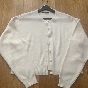 Vit kofta från Gina Tricot - Säljer en stilren vit kofta från Gina Tricot i storlek L. Koftan har rund hals, långa ärmar och knappar framtill. Materialet är mjukt och stickat, perfekt för lager-på-lager. Ribbad kant vid ärmslut och nederkant ger en snygg finish. Enkel att matcha med jeans eller kjol. Hör av er vid frågor💗💗💗