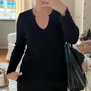 Svart ribbad stickad tröja med v-ringning - Säljer en svart stickad tröja med ribbad struktur och  v-ringad hals från NAKD. Perfekt nu till hösten💕🫰
