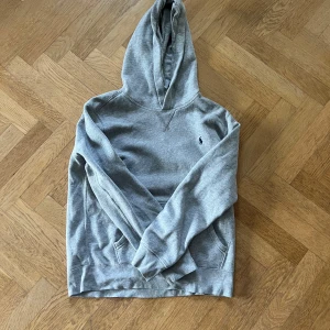 Grå hoodie från Polo Ralph Lauren - Säljer en stilren grå hoodie från Polo Ralph den är storlek L)14-16år, 158-164cm(g. Tröjan har huva, magficka och långa ärmar. Mjuk bomullskvalitet som är perfekt för chill dagar. Passar dig som gillar enkel och clean streetstyle. Fråga mig bara om något! 