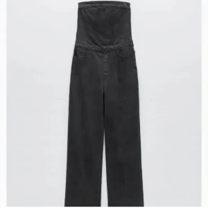 Svart jeansjumpsuit  - Snygg svart jumpsuit med långa och breda ben. Den har en cool, modern siluett som ger en riktigt statement-look. Perfekt för dig som vill sticka ut och gillar trendiga plagg med lite edge. Materialet känns mjukt och har en matt finish. Jumpsuiten har en dragkedja på ena sidan! 