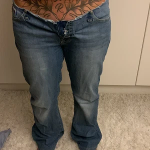 Replay bootcut jeans med låg midja - Säljer ett par blå Replay jeans men står ongen märken för jag har kippat dem.  med bootcut och låg midja. Jeansen har slitna detaljer vid linningen och klassiska bakfickor med broderade X. De är tillverkade i jeansmaterial och har en avslappnad passform med dragkedja och knapp framtill. Midjemått:40cm