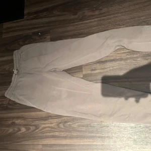 Beige mjukisbyxor från Lindex - Säljer ett par beige mjukisbyxor från Lindex med trycket 'TODAY/TOMORROW' på benet. Byxorna har elastisk midja med snörning och är gjorda i mjukt bomullsmaterial. Perfekta för chill dagar och häng med kompisar.