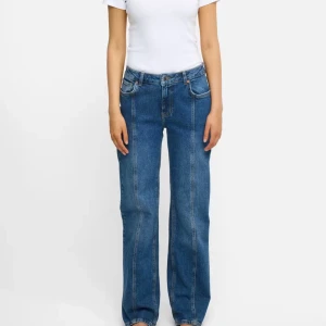 Blå wide jeans från bikbok - Säljer ett par blå jeans från bikbok med wide fit och raka ben. Byxorna har klassisk femficksdesign, hög midja och markerad söm framtill. Materialet är robust jeans och de har en brun patch med logga bak i midjan. Perfekta för en chill och trendig look.