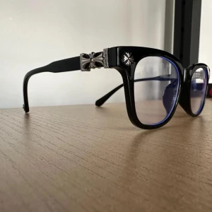 Glasögon. Förbeställ nu! - Vi har inte fått in dem än men ni kan förbeställa nu! Säljer ett par svarta glasögon  med fyrkantig form och coola silverdetaljer på bågarna. Glasen har en lätt blå ton och bågarna är prydda med blommönster i metall. Perfekt för dig som vill sticka ut med en unik och trendig look. Helt nya!