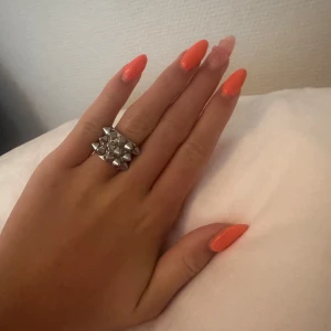 Edblad, Ring med nitar, Silver  - Cool och edgy silvrig ring med fyrkantig form och flera små nitar. Perfekt accessoar för dig som vill sticka ut och ge din look en tuffare vibe. Ringen är bred och har en unik design som verkligen drar blickarna till sig.