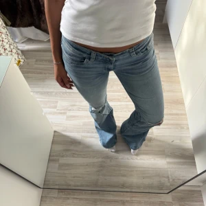 Bootcut ljusblå jeans med slitningar Nelly - Säljer ett par ljusblå lowwaist bootcut jeans med snygga slitningar på knäna.  Sitter som en s/xs