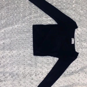 Svart omlott topp från Balancia - Snygg svart omlott topp från Balancia med v-ringning och långa ärmar. Toppen är stickad och har en cool omlott-detalj framtill som ger en trendig vibe💘 S/M