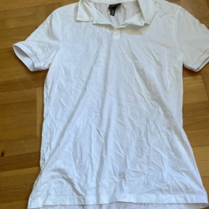 Vit muscle fit t-shirt från H&M - Snygg vit t-shirt från H&M i muscle fit-modell med klassisk krage och korta ärmar. Perfekt för dig som gillar en tightare passform och vill ha en enkel, stilren look. Materialet är mjuk bomull som känns skönt mot huden.