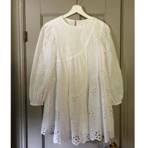 Vit Zara klänning/skolavslutningsklänning - Säljer min favoritklänning.😭Superfin vit kortklänning i bomull med broderade blommor och hålmönster. Klänningen har trekvartsärmar med resår och volangkant nertill. Perfekt för sommarens alla tillfällen och ger en romantisk vibe.💕😇 strl 152, men känns som xxs.