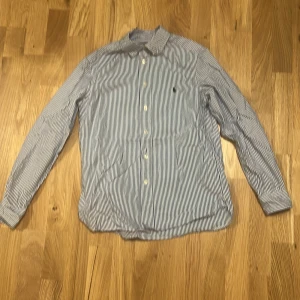 Randig skjorta Polo Ralph Lauren slim fit - Snygg blåvit randig skjorta från Polo Ralph Lauren i slim fit-modell. Skjortan har klassisk krage, långa ärmar och knäppning framtill. Broderad logga på bröstet och tillverkad i mjuk bomull. Perfekt för en clean och stilren look.