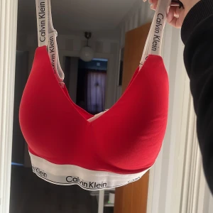 Röd bh från Calvin Klein S - röd bh från Calvin Klein med breda axelband och elastiskt band under bysten med logga, jätteskön verkligen. aldrig använd och köpte den för 599 så vill helst sälja den för 500-450kr men skriv ifall ni har frågar eller om ni vill ha mer bilder å va ni skulle vilja köpa den för🥰