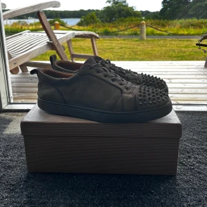 Christian Louboutin skor - Snygga grå sneakers i mocka från Christian Louboutin med svarta nitar på tån och klassisk röd sula. Skorna har snörning och en låg profil, perfekt för dig som vill sticka ut med en edgy detalj. Unik design och riktigt cool vibe. Storlek 44, skick 7/10 mån skada med övrigt bra skick, allt og hänger med🤝🏻, pris går att diskutera✅