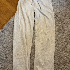 Grå mjukisbyxor från Gina Tricot - Snygga ljusgrå mjukisbyxor från Gina Tricot i storlek M. De har en loose passform med raka ben och snörning i midjan. Perfekta för chill dagar eller när du vill vara extra comfy. Tillverkade i mjukt bomullsmaterial för skön känsla. Har dock fått en sminkfläck på ena benet men som knappt syns😊priset går att diskutera 