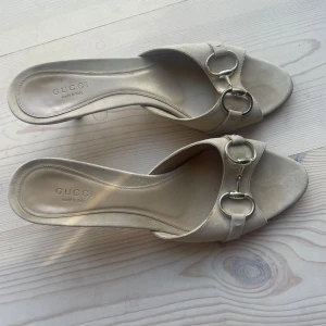 Beige klackskor från Gucci - Snygga beige sandaler från Gucci med öppen tå, träklack och klassiska metallspännen framtill. Skorna är i mocka och har en elegant, tidlös design som passar perfekt till coola outfits. Lyxig känsla! Kan ej ha dom tyvärr därför säljer jag😢😢skriv till mig innan köp bara! 💓