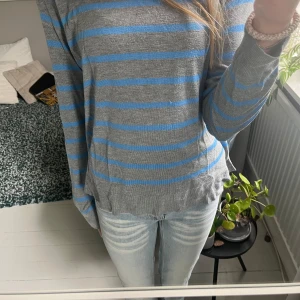 Gråblå randig tröja från Zara - Säljer en grå långärmad tröja från Zara med blåa ränder. Tröjan är i ett otroligt mjukt och skönt material och har en avslappnad passform med ribbade muddar vid ärmslut och hals. Tröjan har en liten defekt på framsidan (se bild 3) men inget som syns tydligt. Säljer även en liknande i svart och röd! Skriv vid fler frågor!!💓