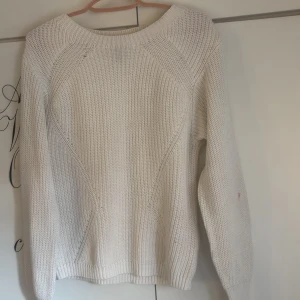 Vit stickad tröja från DIVIDED XS - Vit stickad tröja från DIVIDED i storlek XS. Tröjan har en klassisk rund halsringning, grovstickad struktur och långa ärmar. Perfekt för lager-på-lager och enkel att matcha med jeans eller kjol. Den har tyvärr fått pyttelite röd färg på sig på armen och ett litet litet hål vid halsen.