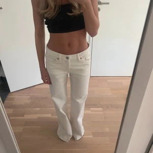 Vita raka jeans från Levis - Säljer ett par vita Levis jeans med rak passform och klassisk femficksdesign. Jeansen har låg midja och är tillverkade i ett stadigt bomullstyg. Perfekta för dig som gillar en clean och stilren look.