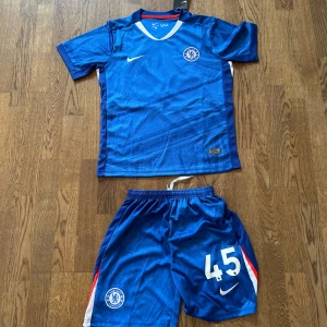 Chelsea hemmatröja och shorts Lavia 45 25/26 - Chelsea fotbollströja med Lavia och nummer 45 på ryggen, även shortsen till. Kittet är helt nytt, har aldrig använts och har lappen på som man ser på bilden. 