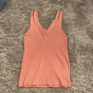 Rosa ribbad linnetopp med v-ringning från Bershka - Supersöt rosa linnetopp med ribbad struktur och v-ringad hals. Toppen är ärmlös och har breda axelband. Inte kommit till användning, därför säljer jag. 
