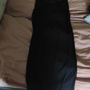 Svart långkjol Gina Tricot S - Säljer en svart långkjol från Gina Tricot i storlek S. Klänningen har en enkel och stilren design med figurnära passform och raka linjer. Materialet är mjukt och stretchigt, vilket gör den bekväm att bära. Säljer pågrund av att jag har två likadana.