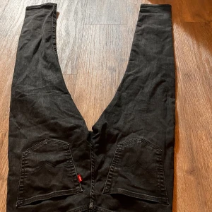 Svarta Levi's 512  jeans W30 L32 - Säljer ett par svarta Levi's 512 jeans med klassisk femficksdesign och raka ben. Jeansen har snygga bakfickor med Levi's röda etikett och är tillverkade i bomull med lite stretch för skön passform. Perfekta svarta jeans för en clean look.