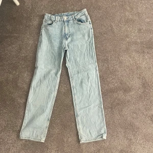 Ljusblå raka jeans - Säljer ett par lågmidjade ljusblå jeans med klassisk femficksdesign och raka ben. Jeansen har knapp och dragkedja framtill samt bälteshällor. Perfekta för en chill och avslappnad stil. Passar dig som gillar enkel och tidlös denim.