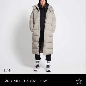 Lång beige pufferjacka från lager 157 - Lång och oversized pufferjacka i beige med huva och dragkedja fram. Perfekt när det är kallt ute. Sparsamt använd 1 vinter och har inge deffekter🥰
