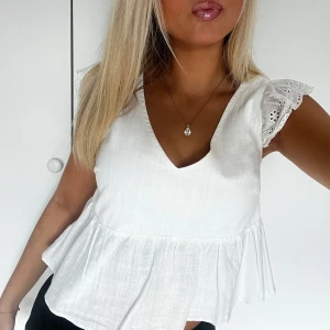 Vit blus med volang och spetsärm - Supersöt vit blus med v-ringning, volang nertill och broderade spetsärmar. Skriv för fler bilder🥰🥰💓💓