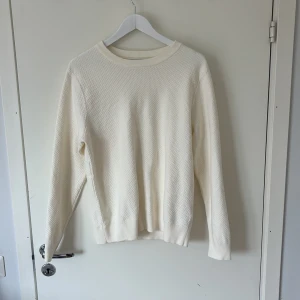 Vit stickad tröja från J.Lindeberg - Säljer en stilren vit stickad tröja från J.Lindeberg. Tröjan har rund halsringning, diskret strukturmönster och långa ärmar. Perfekt för lager-på-lager och enkel att matcha med olika outfits. Priset kan sänkas vid snabb affär och vid ytligare frågor är de bara att höra av dig. 