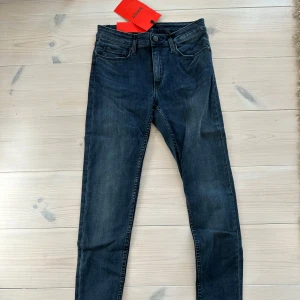 Mörkblå skinny jeans från Whyred - Snygga mörkblå jeans från Whyred med klassisk femficksdesign och skinny passform. Jeansen har en lätt tvättad look, normal midja och raka ben med croppad längd. Perfekta för dig som gillar stilrena och moderna jeans med en cool vibe. Storlek 26/32. Nypris 1200kr rökfritt hem.