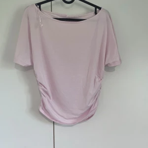 Ljusrosa topp från Gina Tricot🤍 - Säljer en ljusrosa topp från Gina Tricot i mjuk bomull. Modellen har korta ärmar, rund hals och snygg snörning på sidorna som ger en cool rynkad effekt. Perfekt för dig som gillar enkel men trendig stil. Använd med tre gånger, så typ helt ny!🫶🏻