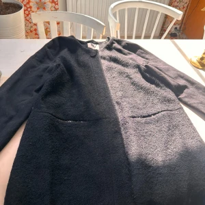 Svart kappa från Vero Moda, storlek L - Svart kappa från Vero Moda i storlek L. Jackan har en enkel design med rund halsringning, stora fickor framtill och stängs med en knapp upptill. Materialet är mjukt och lite fluffigt, perfekt för kyligare dagar. Långärmad och stilren modell som funkar till många outfits.
