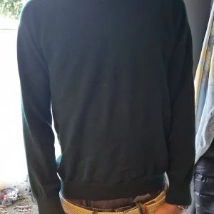 Mörkgrön stickad tröja Tiger of Sweden - Snygg mörkgrön stickad tröja från Tiger of Sweden, tillverkad i italianskt garn. Klassisk rund hals och ribbade muddar vid ärmslut och nederkant. Perfekt för dig som gillar stilrena och enkla plagg med premiumkänsla.