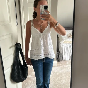 Vit linnetopp med knyt - Supersöt vit linnetopp med tunna axelband som korsas i ryggen, v-ringning och dekorativ rosett. Luftig och perfekt för varma dagar.💕