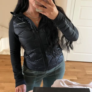 Svart dunjacka från Peak Performance - Säljer en svart dunjacka från Peak Performance med huva och dragkedja framtill. Jackan har quiltad framsida och släta ärmar.