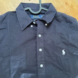 Ralph Lauren Linné skjorta - Säljer denna feta linne skjortan från Ralph lauren, den är i bra skick, den är mörklblå med vita häst logga, storleken är S men sitter mer som xs/s, priset är inte hugget i sten! Hör av er vid andra frågor/ funderingar!